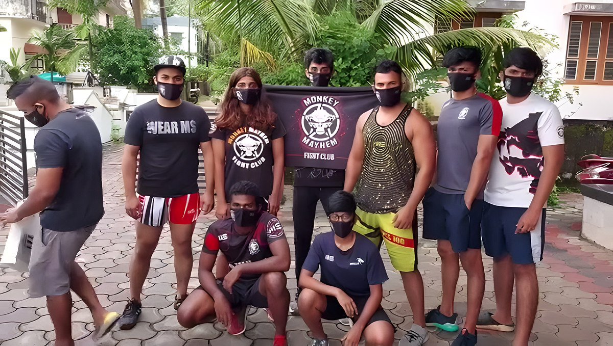 Fight-team members in face masks posing outdoors with the club banner