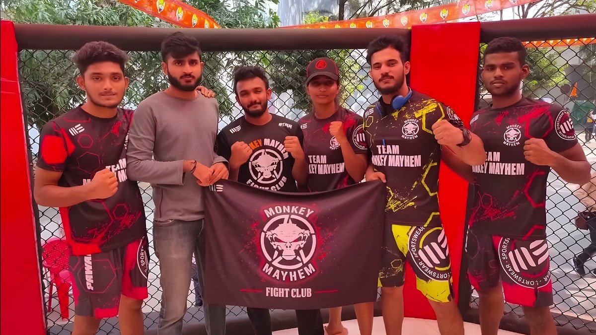 Monkey Mayhem fighters in team jerseys holding the club banner inside a cage