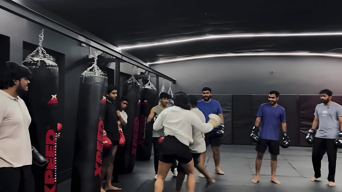 Members in boxing gloves training in pairs across the gym floor
