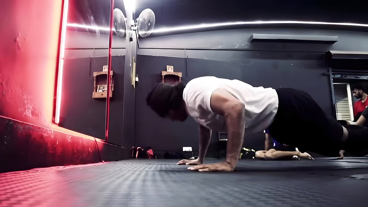 A member doing push-ups on the mats under red and white strip lights