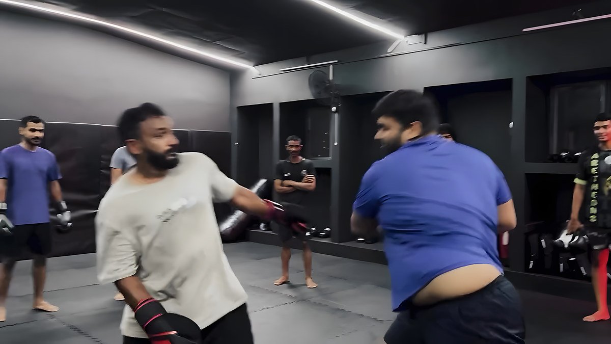 Two members sparring while others train in the background